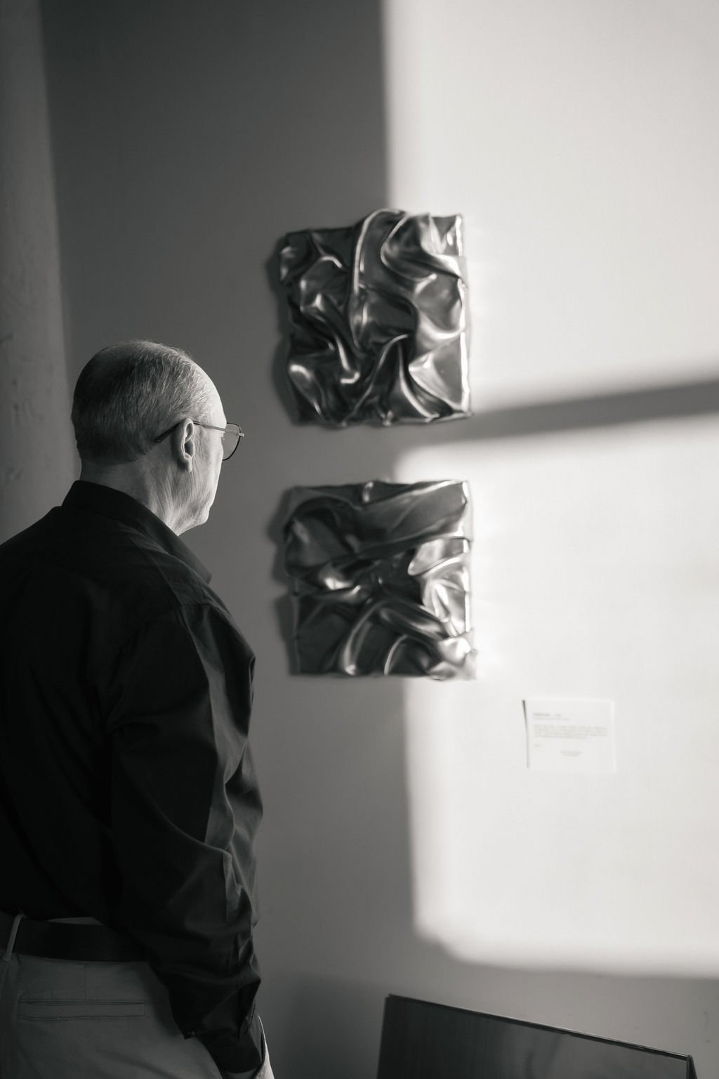 Un visiteur observe le diptyque d’œuvres argentées, noir et blanc