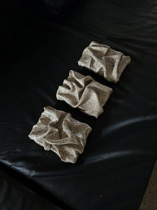 Trois pièces texturées beige moucheté posées sur un canapé en cuir noir